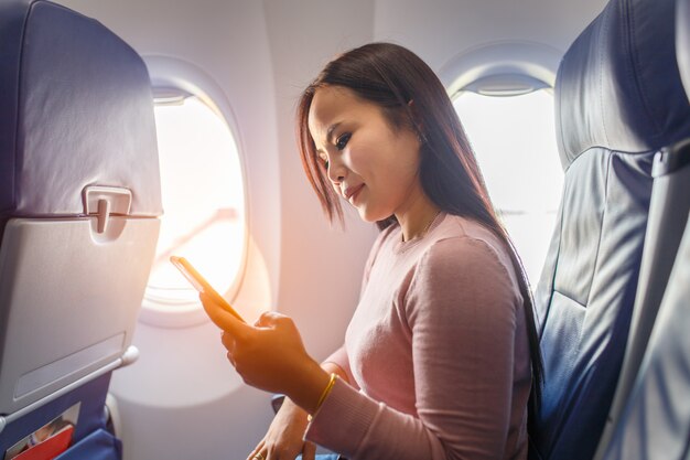 Asian woman use of mobile phone inside airplane