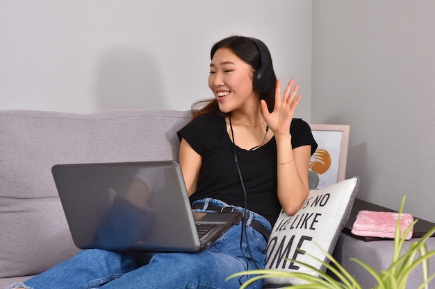 Asian woman using laptop on sofa