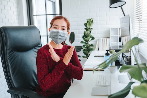 Asian woman using mask sitting on office desk