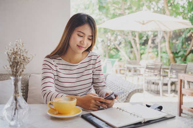 Asian Woman using smartphone in coffee cafe