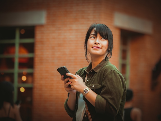 Asian woman using smartphone with happy mood in shopping mall