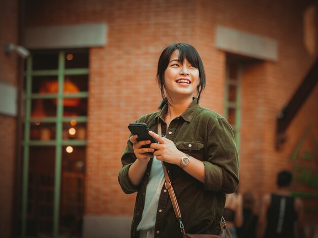 Asian woman using smartphone with happy mood in shopping mall