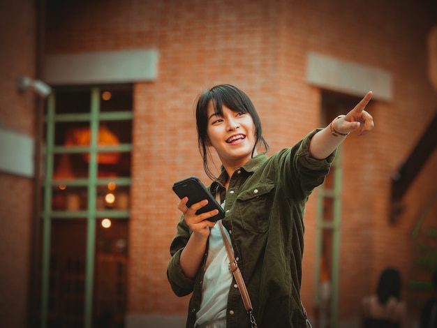 Asian woman using smartphone with happy mood in shopping mall