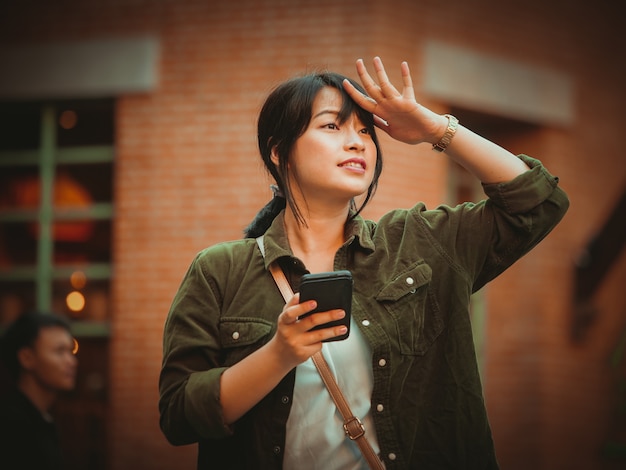 Asian woman using smartphone with happy mood in shopping mall