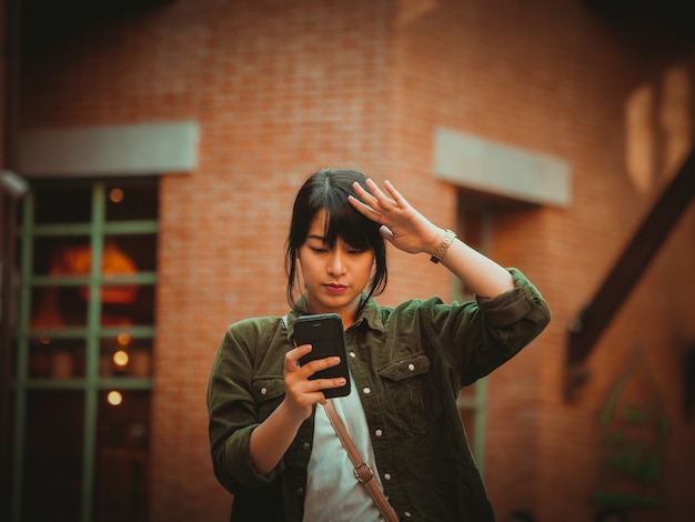 Asian woman using smartphone with happy mood in shopping mall