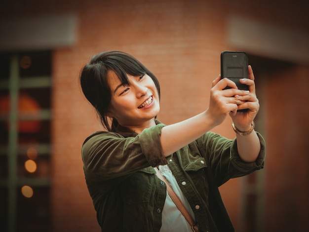 Asian woman using smartphone with happy mood in shopping mall