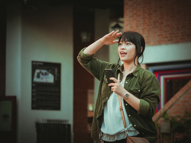 Asian woman using smartphone with happy mood in shopping mall