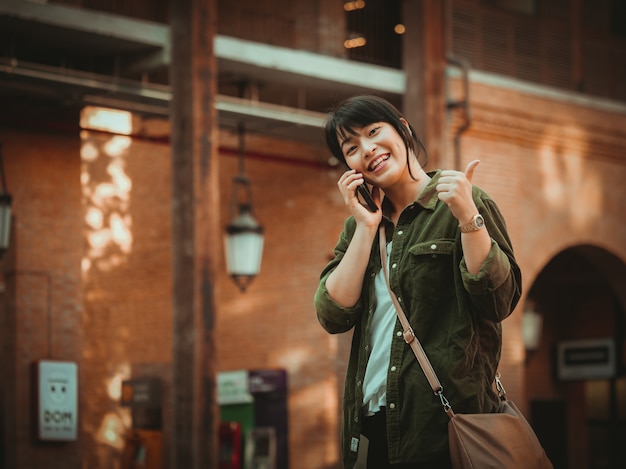 Asian woman using smartphone with happy mood in shopping mall