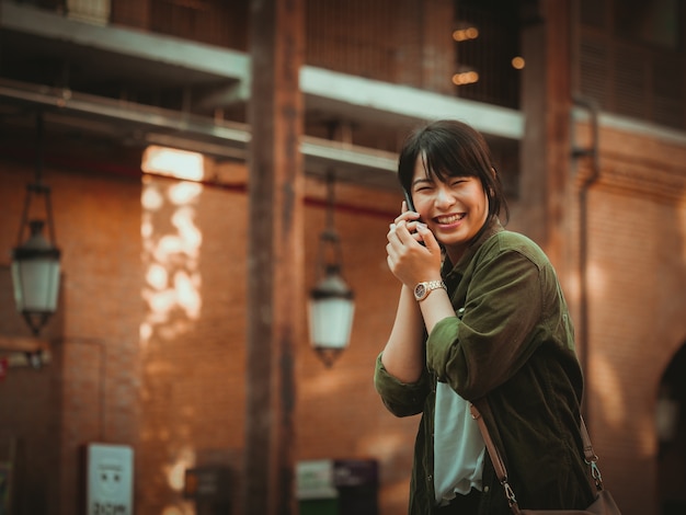 Asian woman using smartphone with happy mood in shopping mall