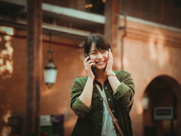 Asian woman using smartphone with happy mood in shopping mall