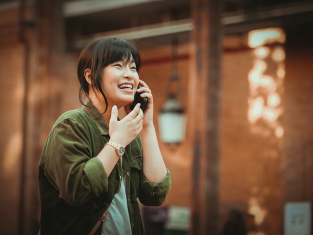 Asian woman using smartphone with happy mood in shopping mall