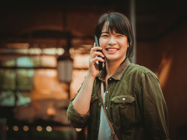 Asian woman using smartphone with happy mood in shopping mall