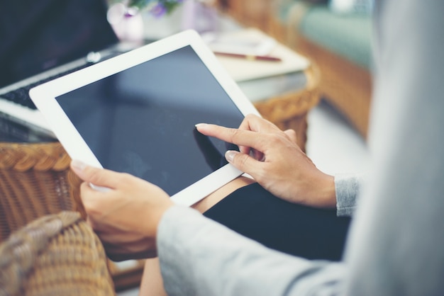 Asian woman using tablet computer in cafe drinking coffee