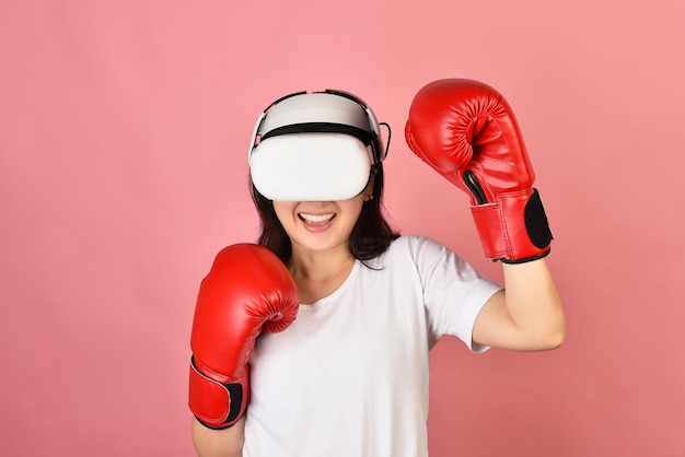 Asian woman using vr glasses Working out with boxing video games application from virtual reality headset Young woman enjoy new fitness experience by vr technology Studio shot