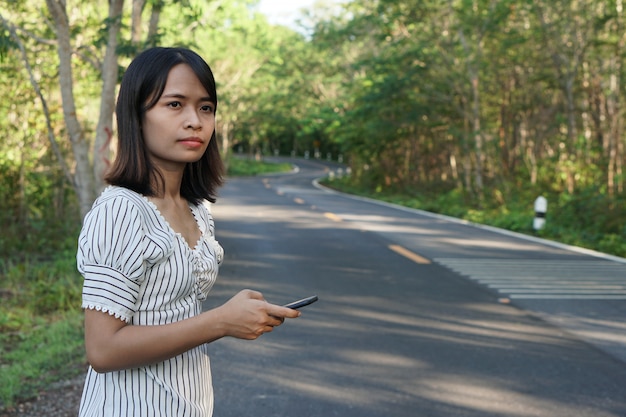 Asian woman waiting for a bus on the side of the road