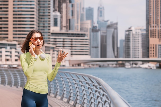 Asian woman was running along the Dubai Marina embankment and annoyed talking on the phone because of a conflict or poor communication