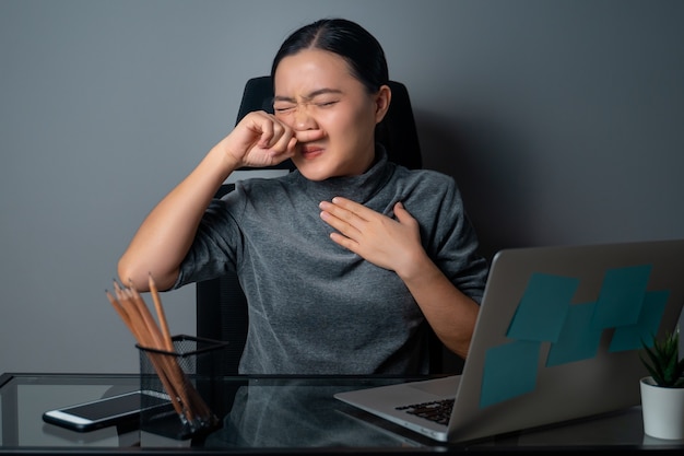 Asian woman was sick with fever, working on a laptop at office 