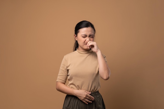 Asian woman was sick with sore throat coughing sneezing and standing isolated on beige background