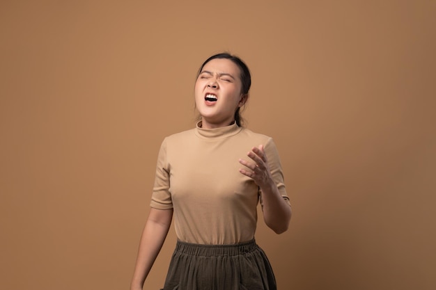 Asian woman was sick with sore throat coughing sneezing and standing isolated on beige background