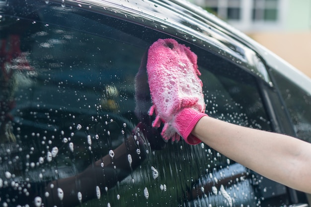 Asian woman washing car roof with microfiber cloth