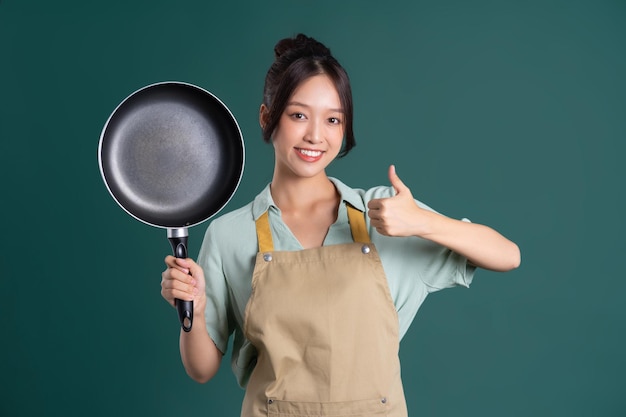 Asian woman wearing apron and holding a pan