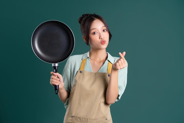 Asian woman wearing apron and holding a pan