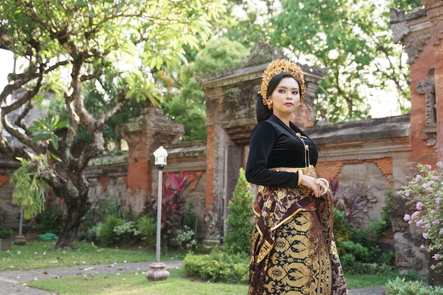 Asian woman wearing balinese kebaya and woven cloth standing