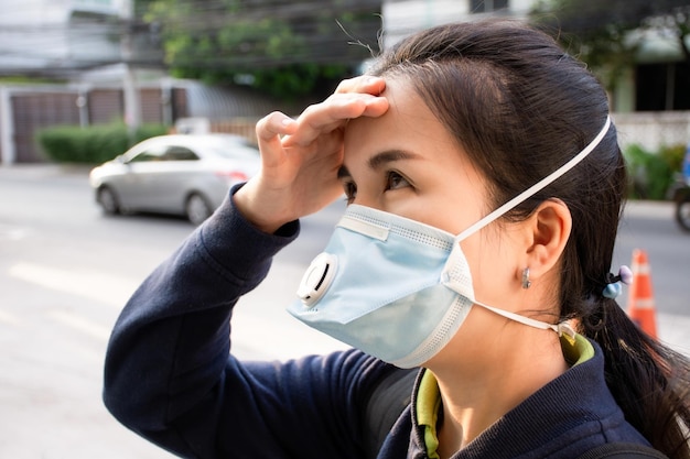 Asian woman wearing a dust protection face mask in city street outdoor with air pollution