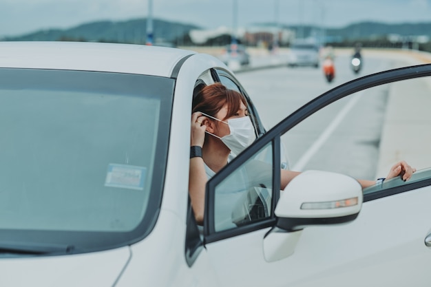 Asian woman   wearing protective face mask protection safety before getting out of the car during coronavirus covid-19 outdoor curfew pandemic