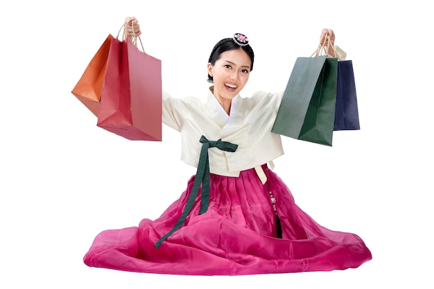 Asian woman wearing a traditional Korean national costume Hanbok sitting and holding shopping bags