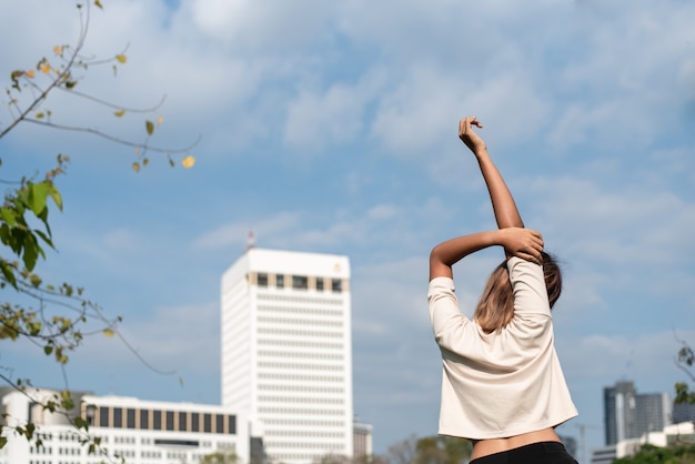 Asian woman wearing white shirt in a cooldown posture after exercising in the park