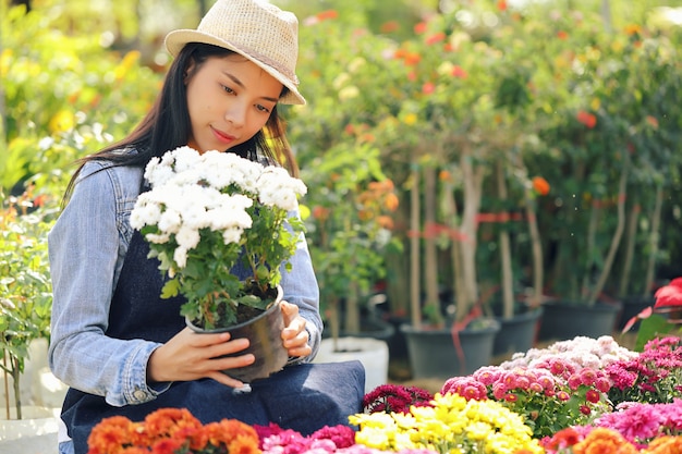 An Asian woman who owns a flower garden business is counting the flowers to match the customer order.