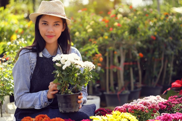 An Asian woman who owns a flower garden business is counting the flowers to match the customer order.