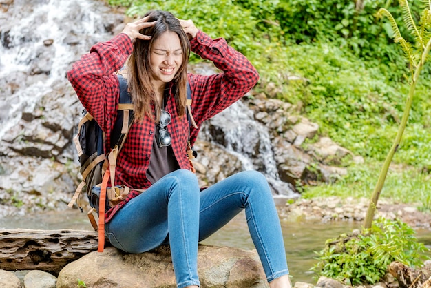 Asian woman with backpack feeling headache