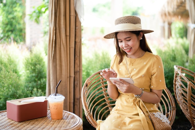 Asian woman with beautiful smile reading good news on mobile phone during rest in coffee shop happy female watching her photos on cell phone while relaxing in cafe during free time