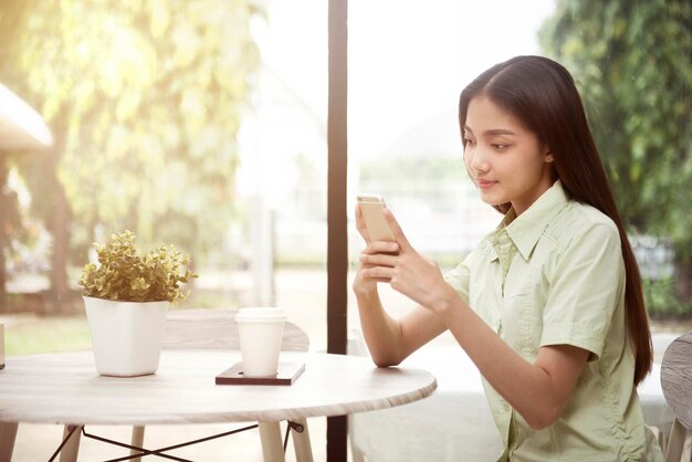 Asian woman with coffee on the table using a mobile phone in the coffee shop