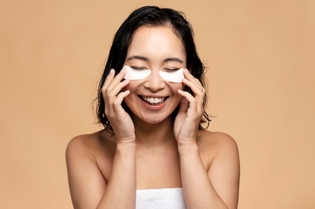 Asian woman with eye patches on face and bare shoulders posing