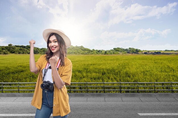 Asian woman with a hat and camera with an excited expression