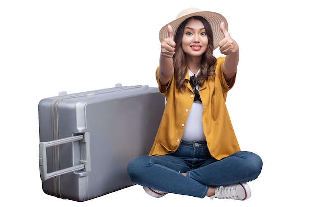 Asian woman with a hat and suitcase sitting showing thumb up