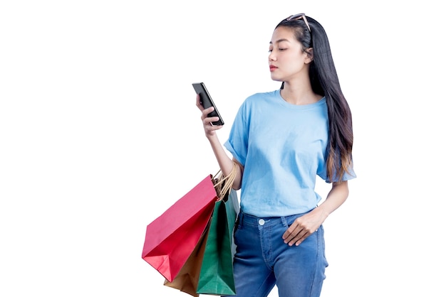 Asian woman with sunglasses carrying shopping bags holding mobile phone isolated over white wall