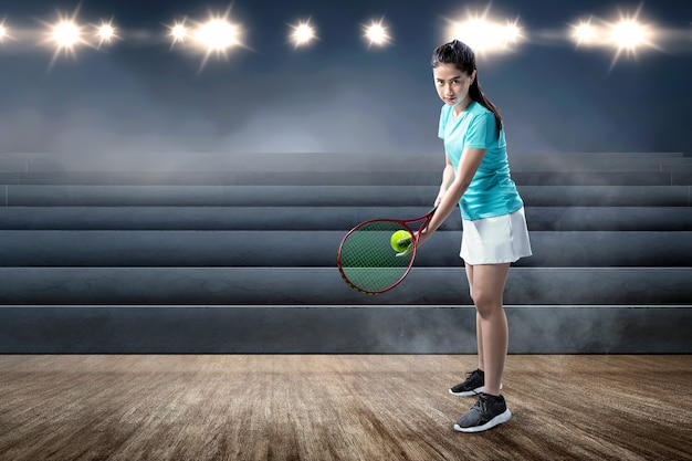 Asian woman with a tennis racket and ball in her hands ready in serve position