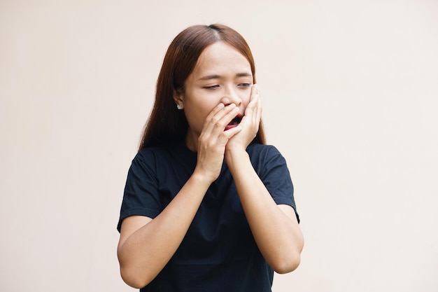 Asian woman with toothache touches cheek with her hand