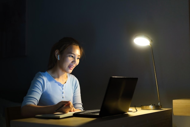 Asian woman work at home are sitting at work with colleagues or managers via video call at night at home.