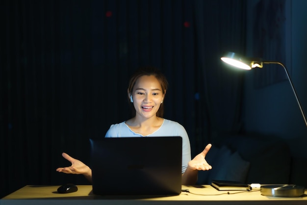 Asian woman work at home are sitting at work with colleagues or managers via video call at night at homexD