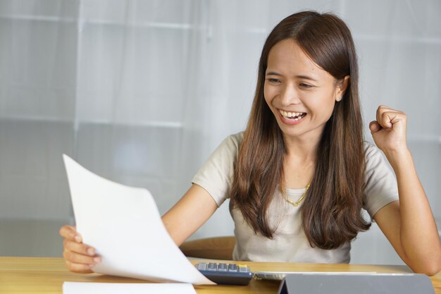 Asian woman working at home Happy after having increased profits