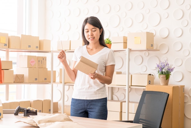 Asian woman working at home with packing boxes