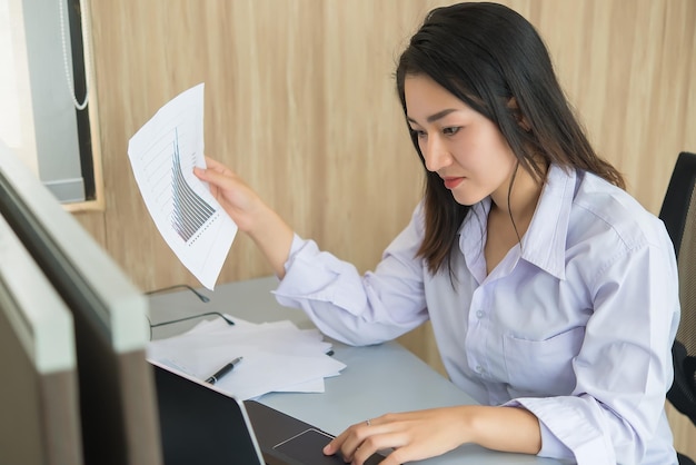 Asian woman working overtime in the office Business a lot of workCheck file with laptopThailand people with office uniform