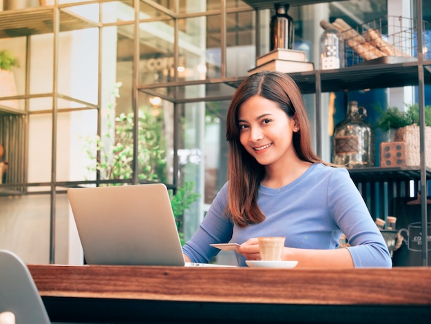 Asian woman working with laptop in coffee shop.