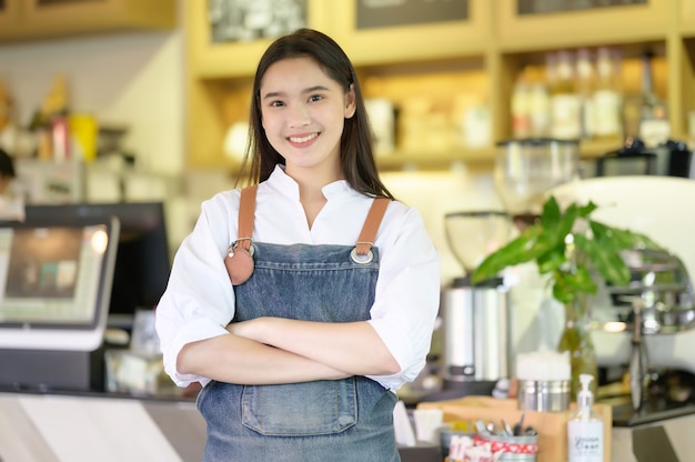 Asian women Barista smiling and using coffee machine in coffee shop counter