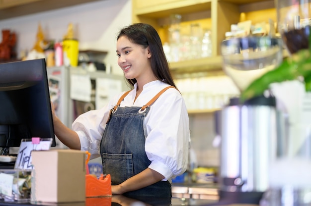 Asian women Barista smiling and using coffee machine in coffee shop counter